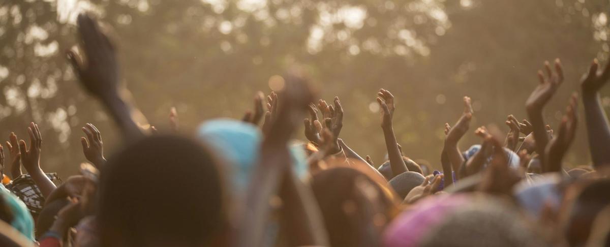 A large group of people raising their hands at an outdoor community event - Photo by Caleb Oquendo on Pexels